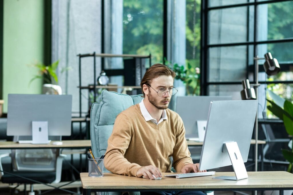 Serious and scorn-centered man in the office at work with a computer, man typing thoughtfully on